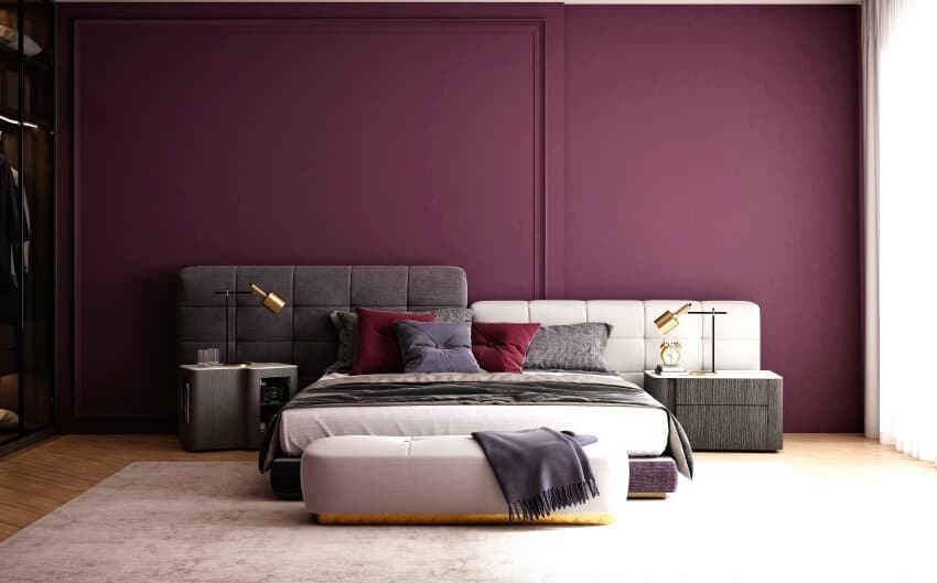 Bedroom with deep purple wall, white and gray bed, and golden table lamps
