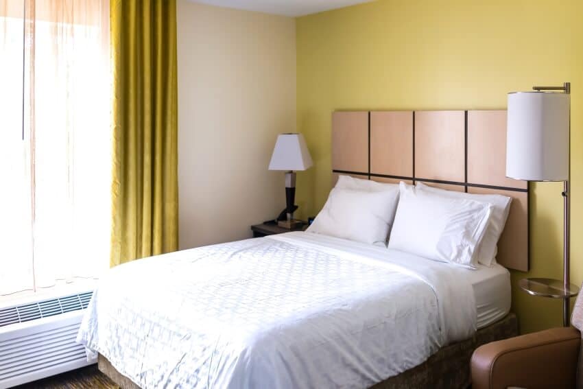 Bedroom with light yellow wall, white pillows and panel headboard