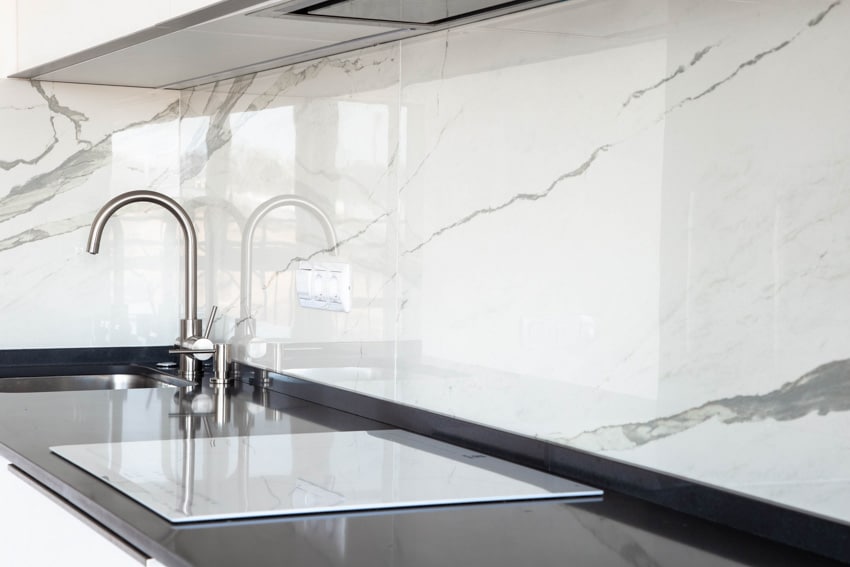 Modern kitchen with Calacaltta marble slab backsplash, sink, stove, faucet, and countertop
