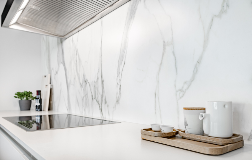 Modern kitchen with Calcatta gold marble backsplash, stove, countertop, and range hood