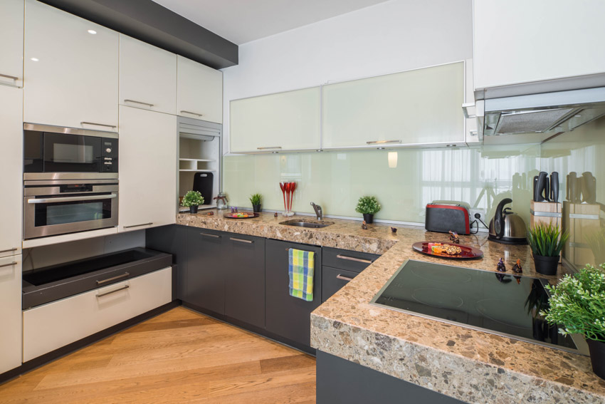 Modern kitchen with DIY recycled glass countertop, white cabinets, glass backsplash, stove, oven, and wood floors