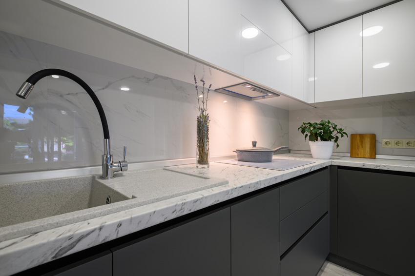 Kitchen with black faucet, ceramic sink, marble backsplash and handleless cabinets