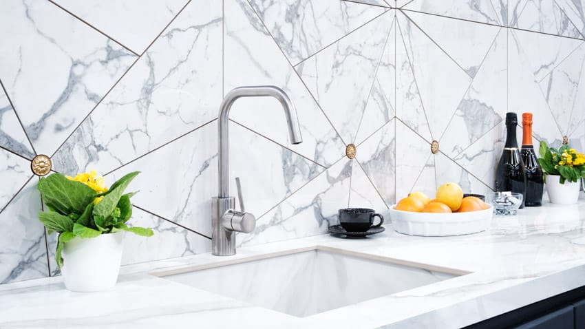 Modern kitchen with geometric Calacaltta marble slab backsplash, countertop, sink, faucet, and countertop