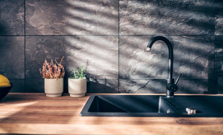 Modern kitchen with wood countertop, black slate backsplash and sink