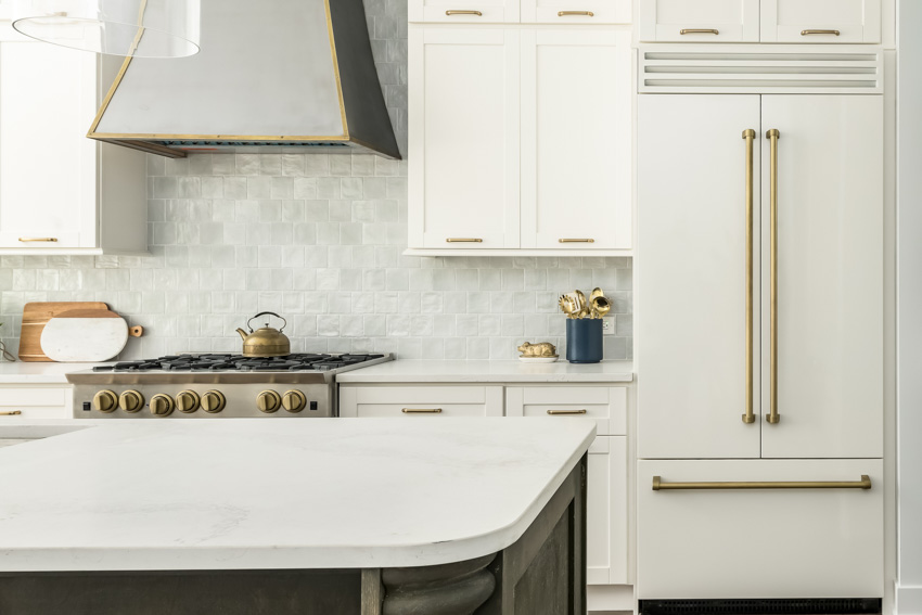 Cabinets with gold handles, round edged counter and oven with kettle on stove