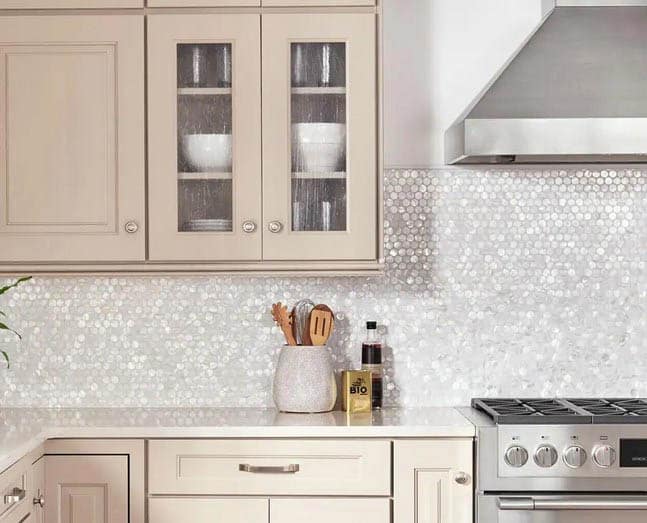 Mother of pearl backsplash, steel oven and range and beige cabinets