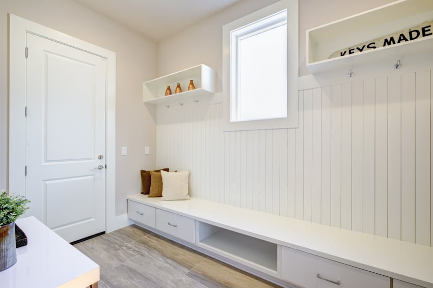 Mudroom with beadboard wall, drawers, window, shelves, and white door