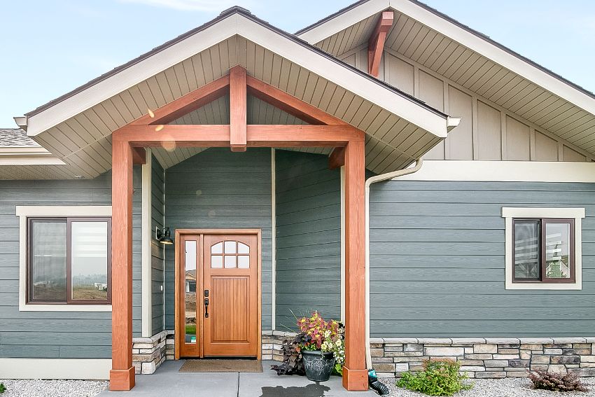 Newly built home with blue and brown exterior, stained okoume veneers front door and columns