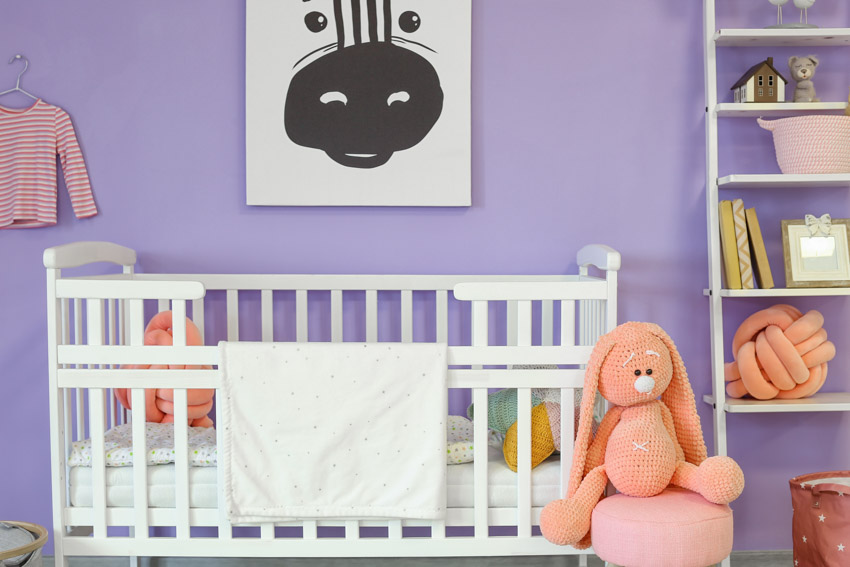 Nursery room with crib, shelves, and lavender painted wall