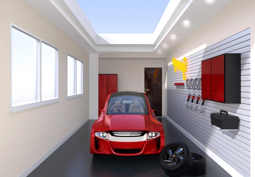 Red car slat wall toolbox and spare tires in a garage with skylight window