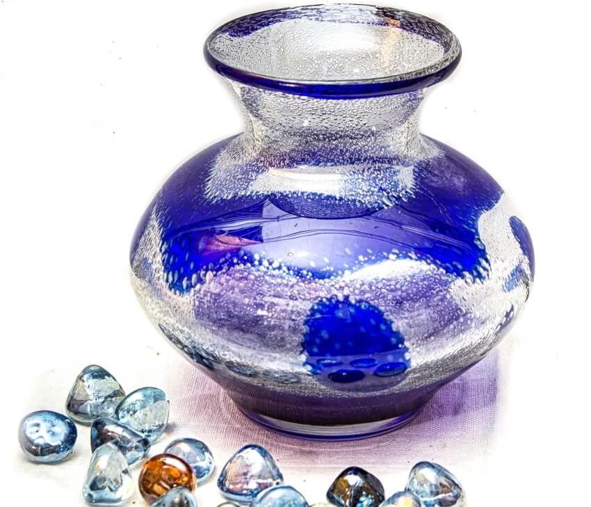 Retro blue glass vase with glass stones filler on white background