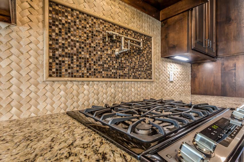 Rustic kitchen with granite countertop, stove, wood cabinets, and mosaic tile backsplash