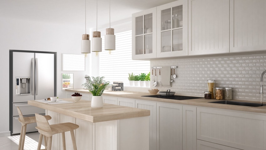 Scandinavian style kitchen with subway tile backsplash, wood countertops, and glass cabinets