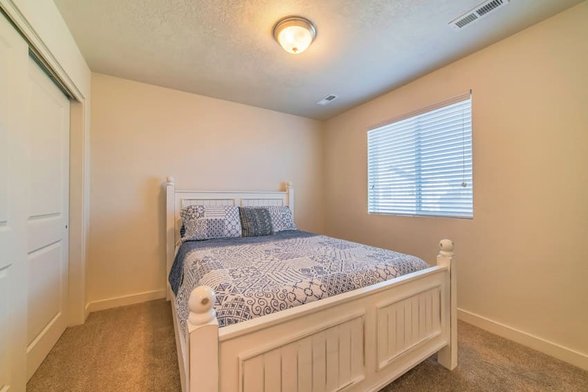 Bedroom with flush type light, bed, comforter, pillows, and window blinds