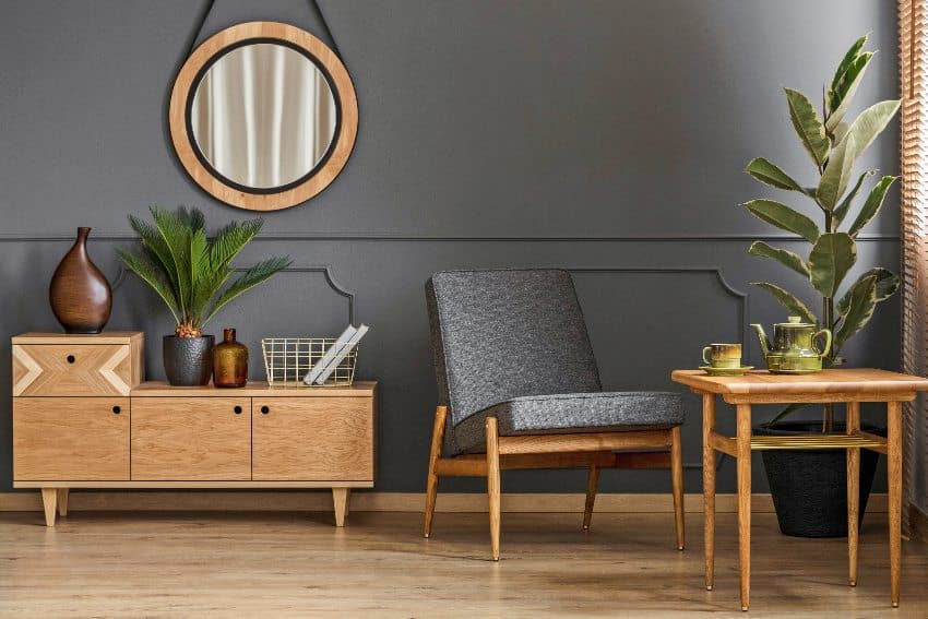 Sitting corner with okoume furniture in a grey room interior with mirror and cabinet