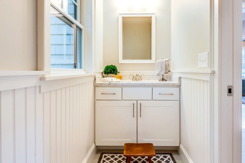A small bathroom vanity with vertical shiplap siding and nice wood step stool