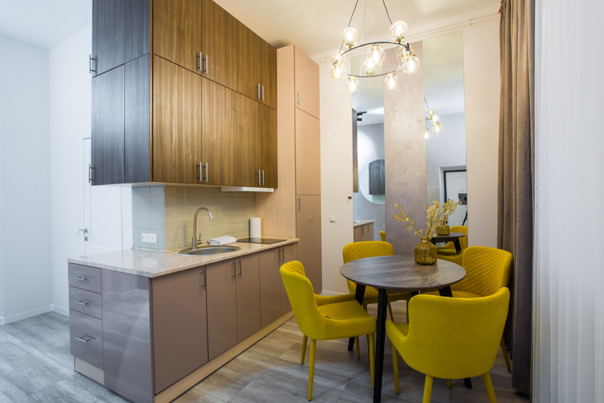 Small kitchen with table, chairs, chandelier, countertop, sink, faucet, and wood veneer cabinets