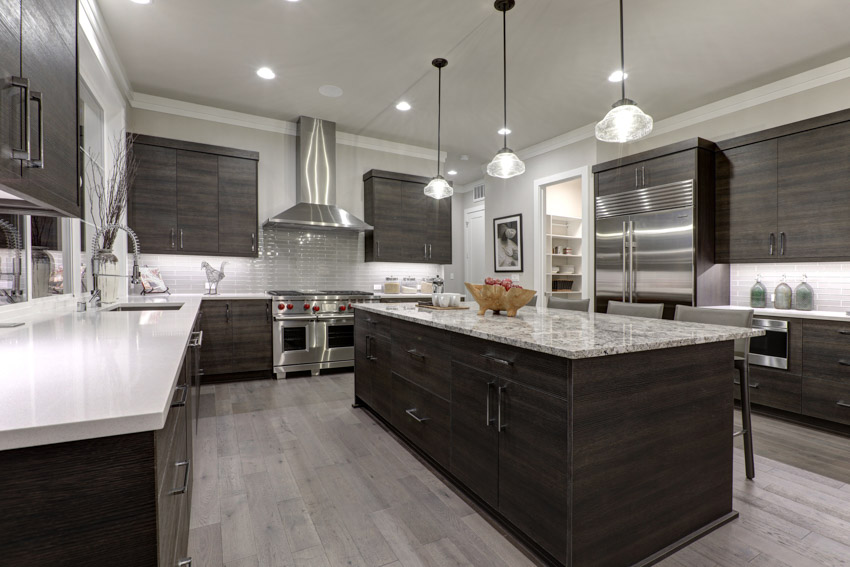 Spacious kitchen with island, countertop, wood veneer cabinets, wooden flooring, pendant lights, range hood, and refrigerator