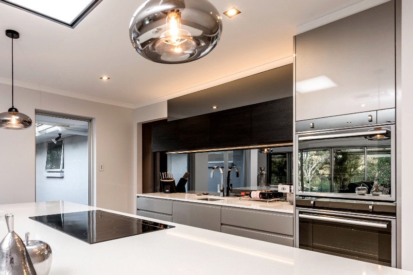 Stunning kitchen with modern pvc kitchen cabinets, mirror backsplash and clean white quartz countertop