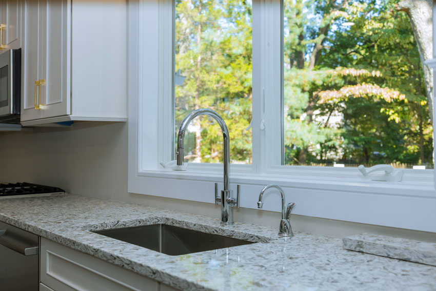 Traditional kitchen with recycled glass countertop, sink, faucet, cabinets, and window