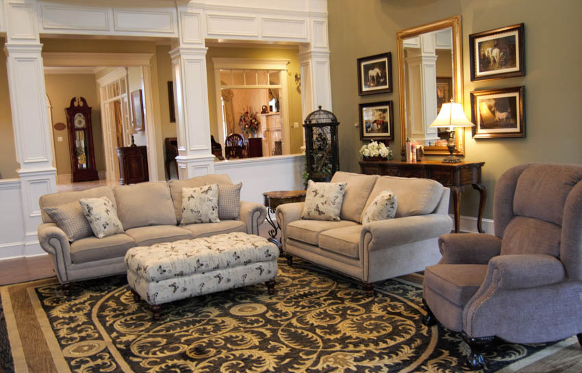 Traditional living room with carpet, ottoman, cushioned chair, sofas, mirror, sofa table, and different decor pieces