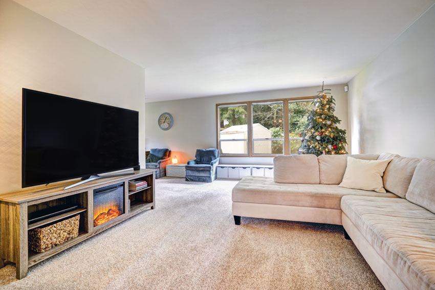 Room with tv console. sectional, Christmas ttree and window with wood trim
