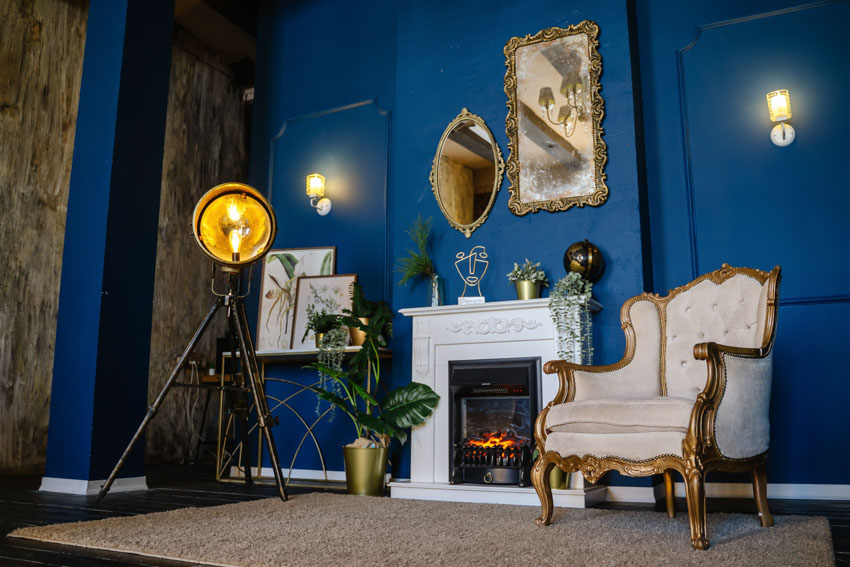 Traditional living room with wall mounted electric fireplace with mantel, accent chair, floor lamp mirror, and blue walls