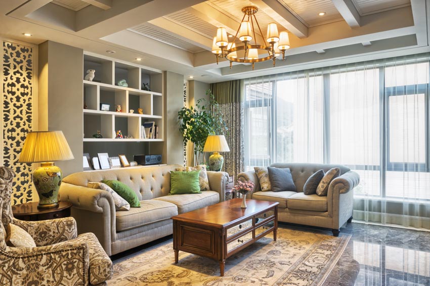 Traditional living room with wood coffee table, couch, loveseat, shelves, chandelier, and windows