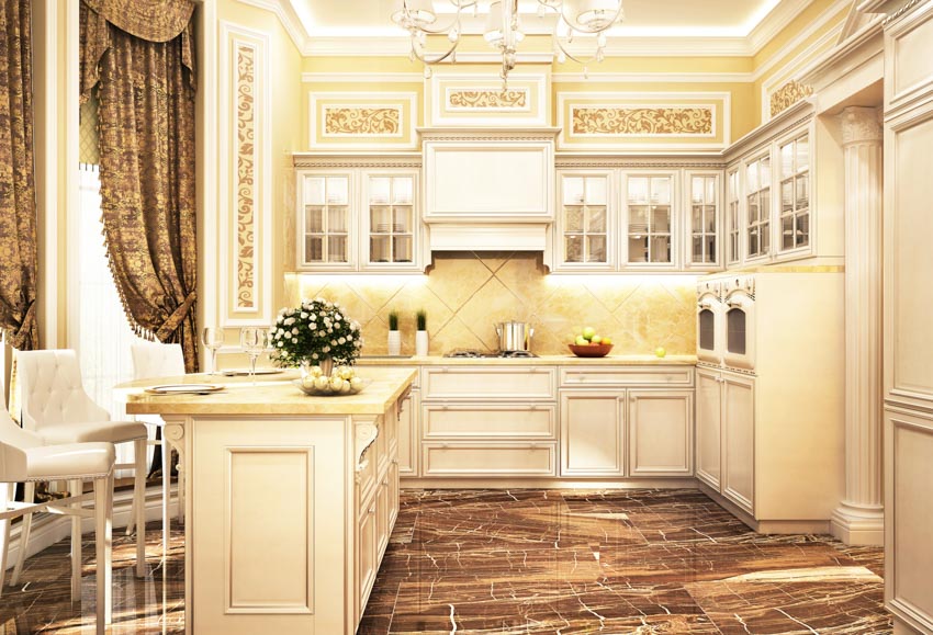 Kitchen with gold lighting scheme, bar counter, tufted chairs, backsplash and countertops