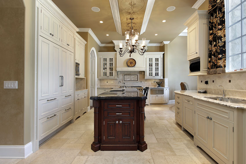 Kitchen with wooden island, travertine tiles, chandelier and printed curtains