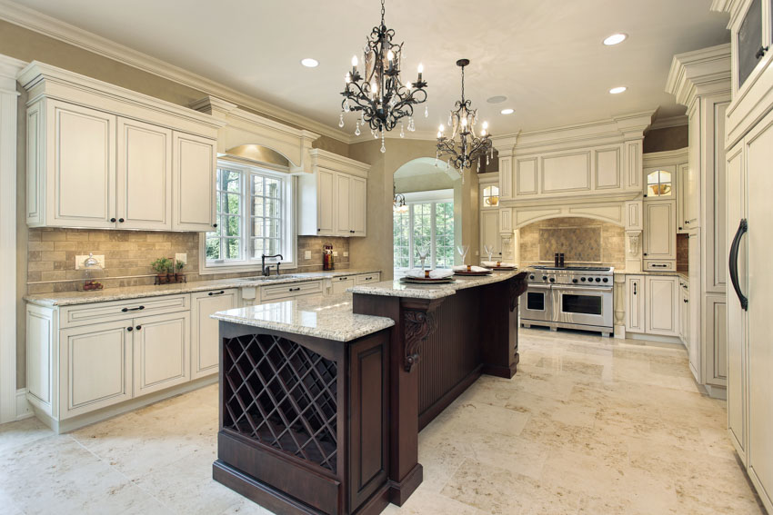 Victorian kitchen with white cabinets, tile backsplash, wood island, countertops, oven, chandeliers, and windows