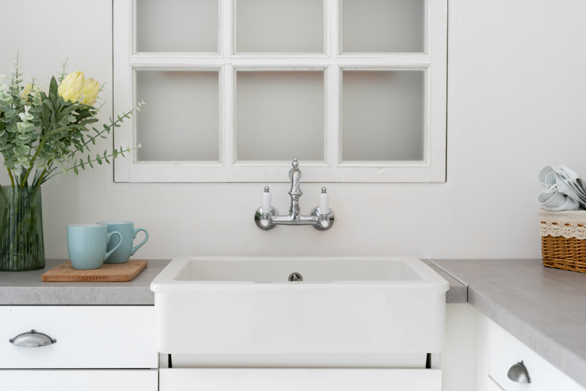 Kitchen with farmhouse kitchensink, faucet in chrome finish, grey soapstone counters