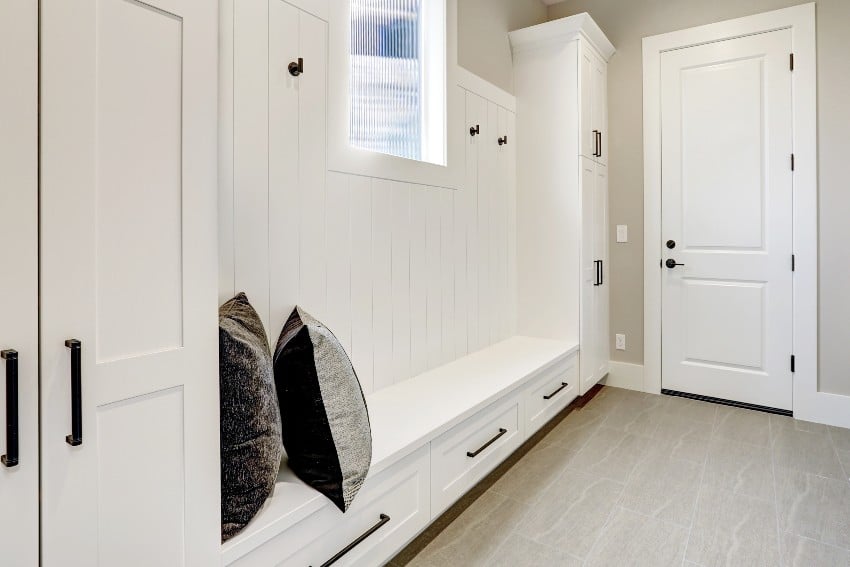 A white clean hallway in modern house with a vertical shiplap wall behind the bench with drawers