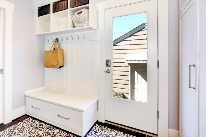 White hallway with vertical shipalap wall behind bench with drawers, storage cabinet with hangers, and storage units on the top