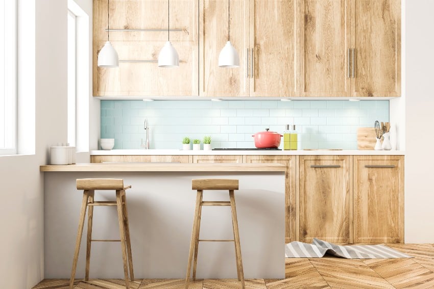 White Scandinavian style kitchen with blue tiled and white walls, a wooden floor, okoume countertops and cabinets and a bar with stools