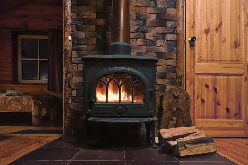 Wooden cabin interior with wood burning stove for heating and brick accent wall