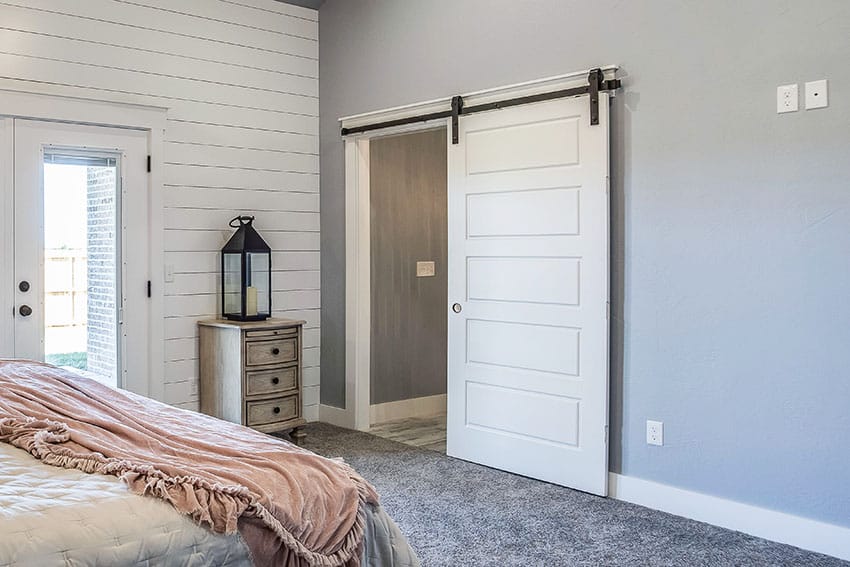 Bedroom with sliding door, side table, gray paint and carpet floor