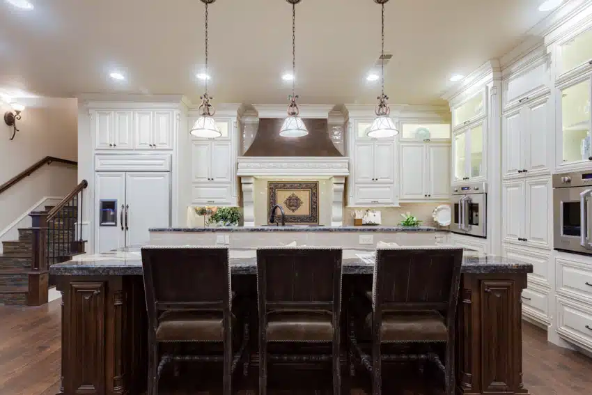 French country kitchen with island, chairs, tile backsplash, white cabinets, stove, wood floors, and pendant lights