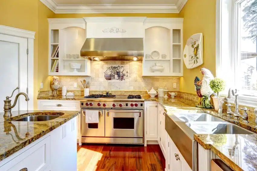French country kitchen with painted tile backsplash, white cabinets, stove, oven, range hood, granite countertop, wood flooring, sink, faucet, and windows