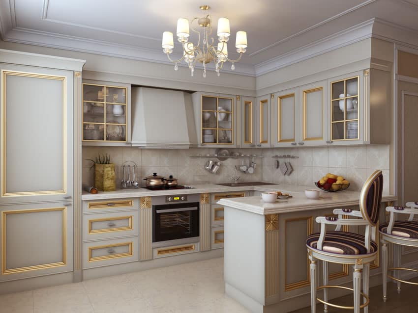 French country kitchen with white cabinets, gold accent, tile backsplash, chairs, range hood, stove, and chandelier