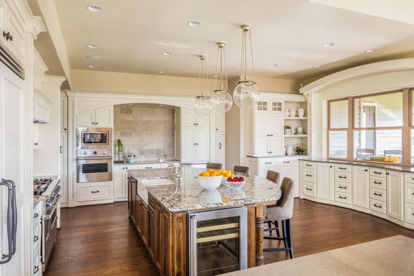 Kitchen with peninsula seating, wood plank flooring, chairs, backsplash and windows