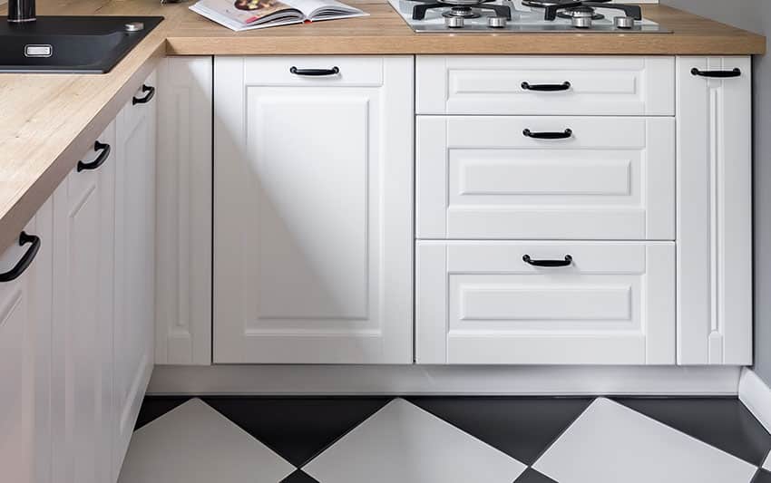 White kitchen cabinets with raised front drawer wood countertop