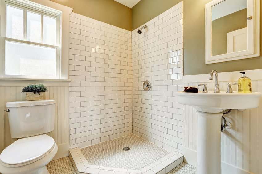 Bathroom shower with white subway and tile black grout wall, toilet, sink, and mirror