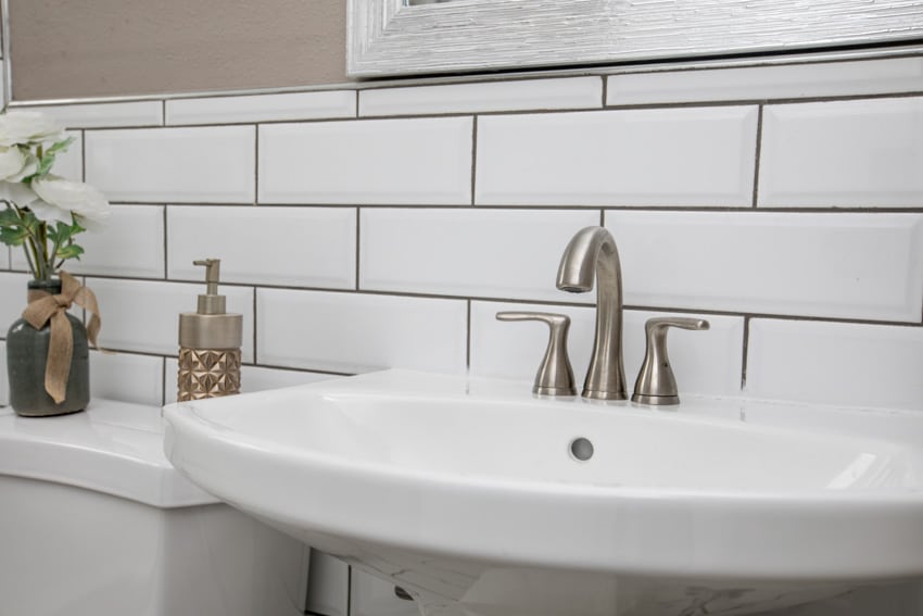 Bathroom with white subway tile and black grout backsplash, sink, and faucet