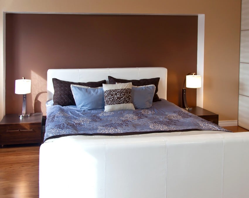 Bedroom interior design with espresso brown walls, wooden floors and white bed