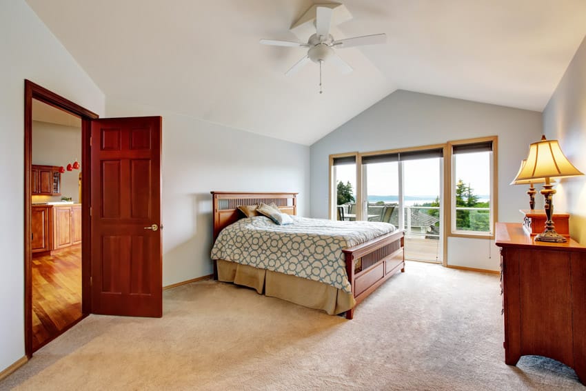 Bedroom with ceiling fan, dresser, lamp, mission style bed, comforter, glass door, and window