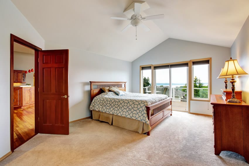 Room with ceiling fan, sliding doors, dresser and wooden door