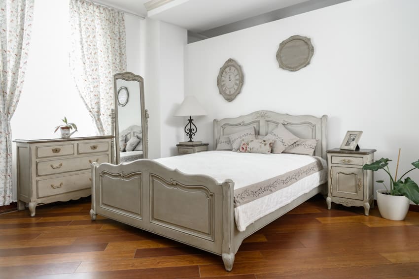 Bedroom with chalk paint drresser, bed frame, nightstand, mirror, wood flooring, window, and curtains