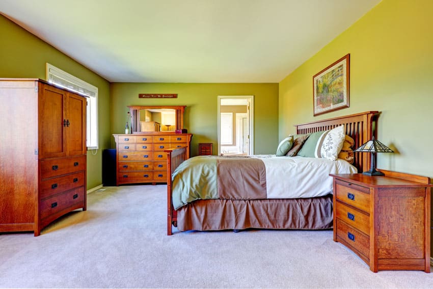 Green colored walls, wood nightstand, cabinet and chest of drawers