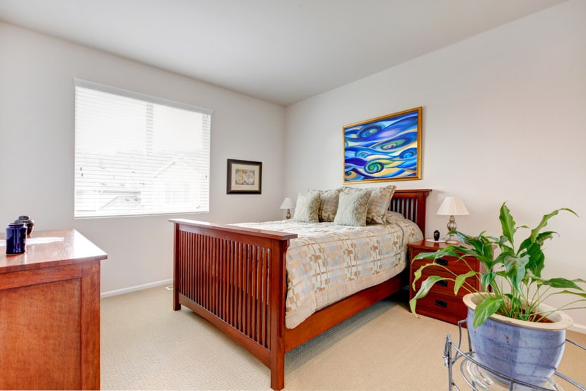 Room with wooden bed, bedside tables, and windows with blinds